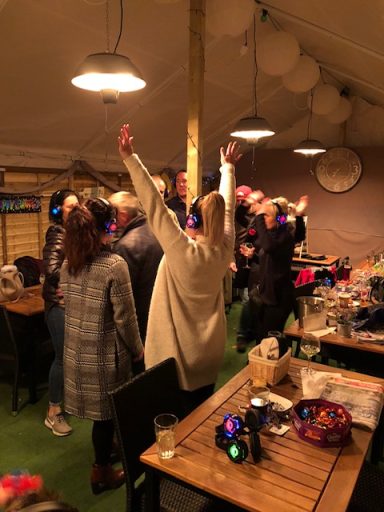 People dancing and celebrating indoors with festive decorations and lights.