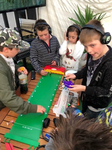 A group of children wearing headphones engaged in a hands-on activity at a table.